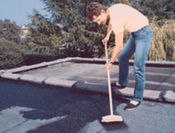 Un homme applique un primer d'apprêt sur le toiture