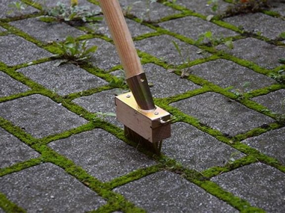 onkruid los maken met houten onkruidborstel